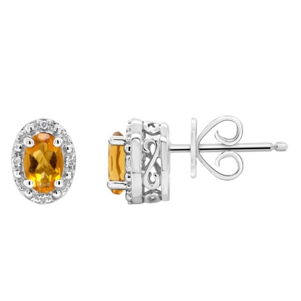 A pair of earrings with an oval cut citrine and diamond halo.